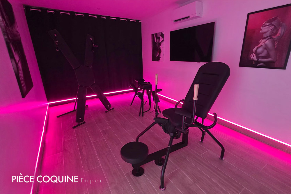 Room with pink LED lighting featuring BDSM furniture: a padded bondage chair, a bench, and equipment along the walls under black curtains.
